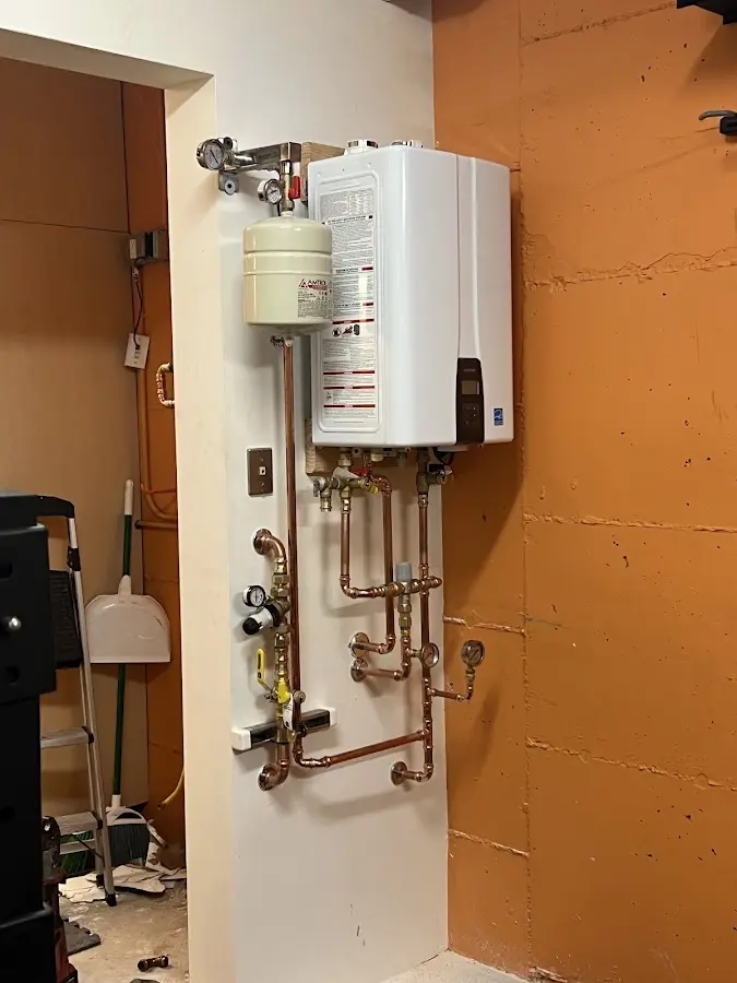 Plumbing technician inspecting water heater connections in Burton